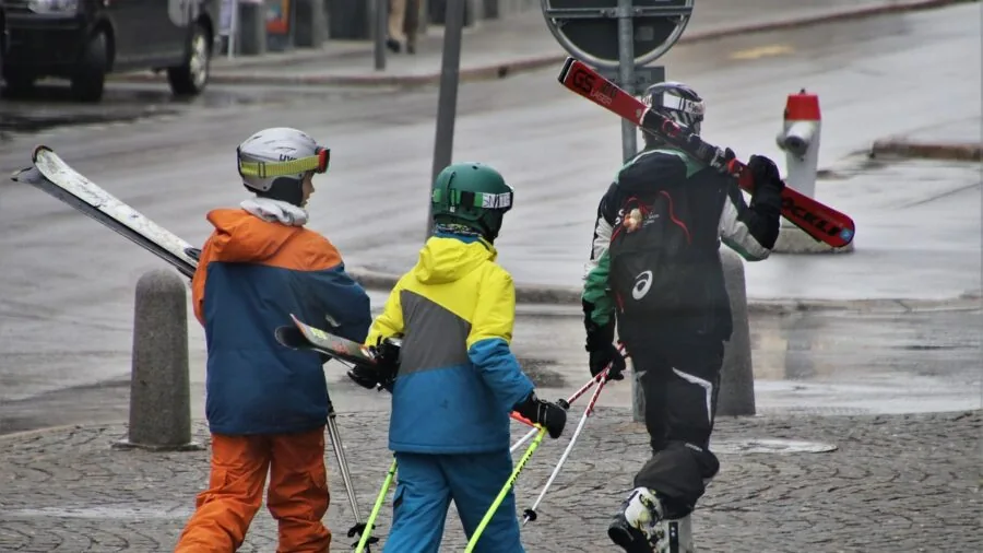 Skier on snowy slope reaching into jacket pocket to access essentials during winter skiing activity