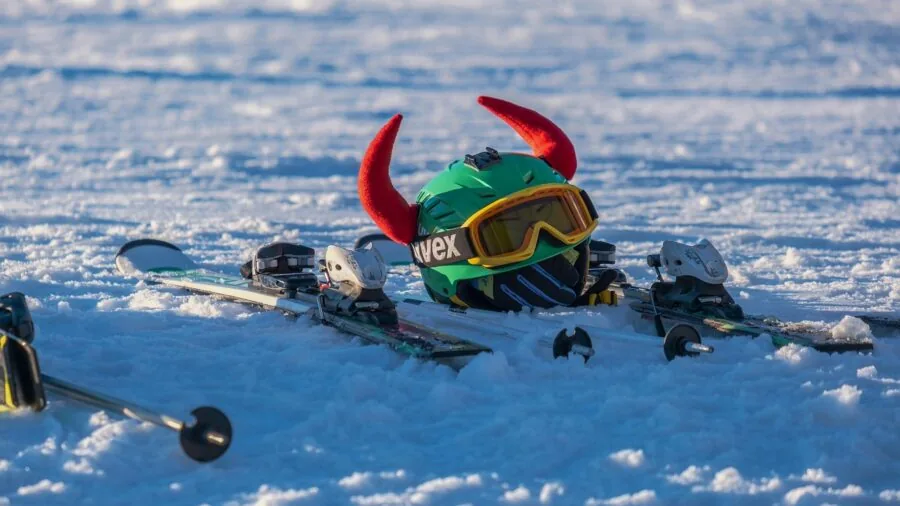 Skier on snowy slope wearing protective helmet and goggles integrated together