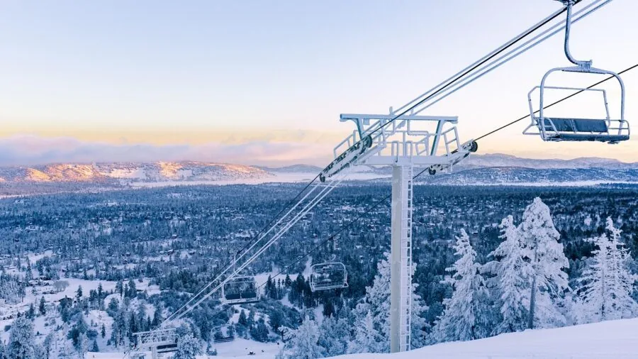 Skier riding chairlift up snowy mountain slope at ski resort