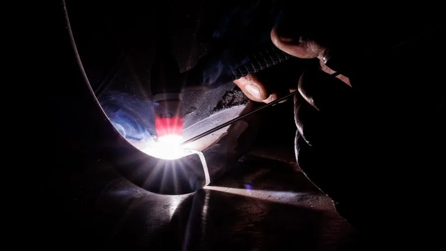 Skilled technician carefully applying fluid to metal workpiece in workshop setting