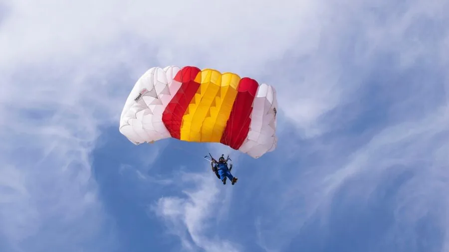 Skydiver in freefall with deployed parachute canopy against sky during descent