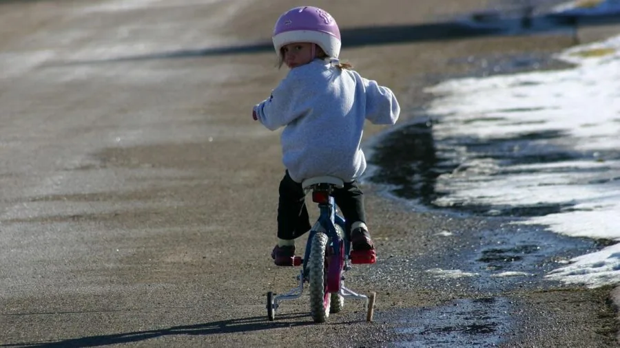 Small child focused on riding a simple bicycle outdoors, developing balance and cycling skills