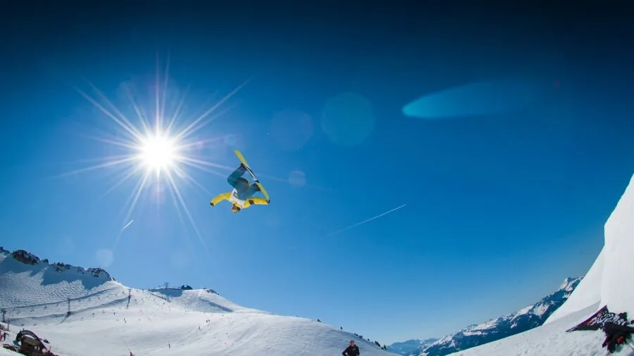 Snowboarder checking boot fit before riding down snowy mountain slope