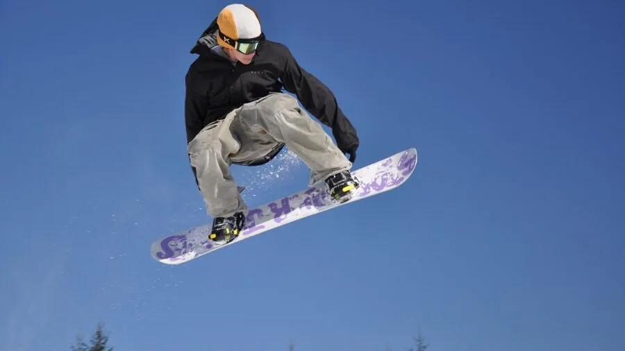 Snowboarder riding down snowy mountain slope during winter conditions with fresh powder