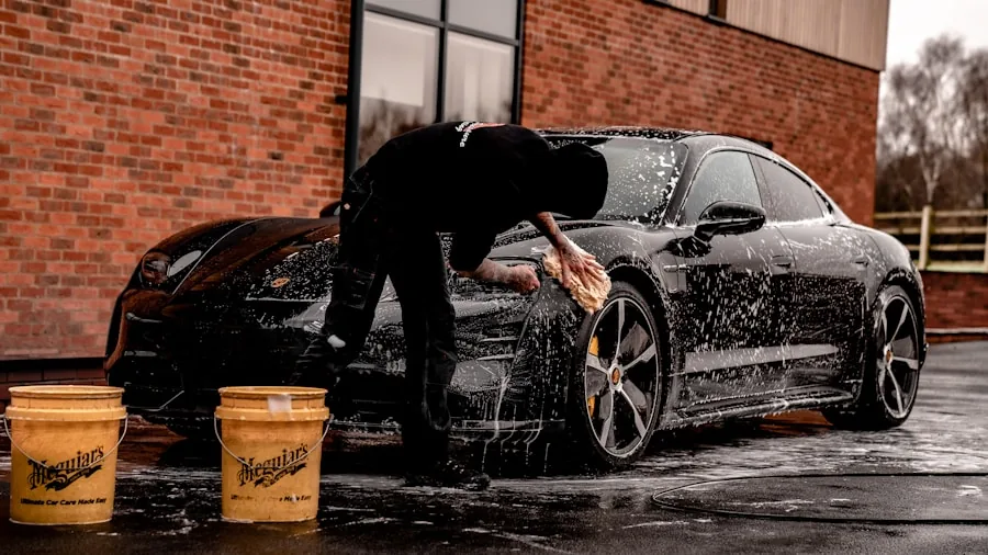 Someone carefully applying protective wax to a car's surface outdoors
