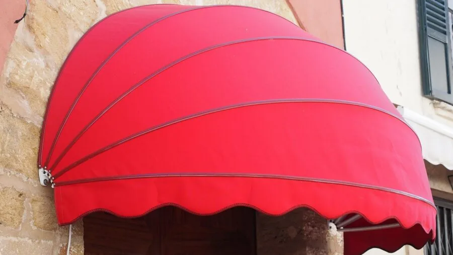 Someone installing a retractable awning on an RV during a camping trip in nature