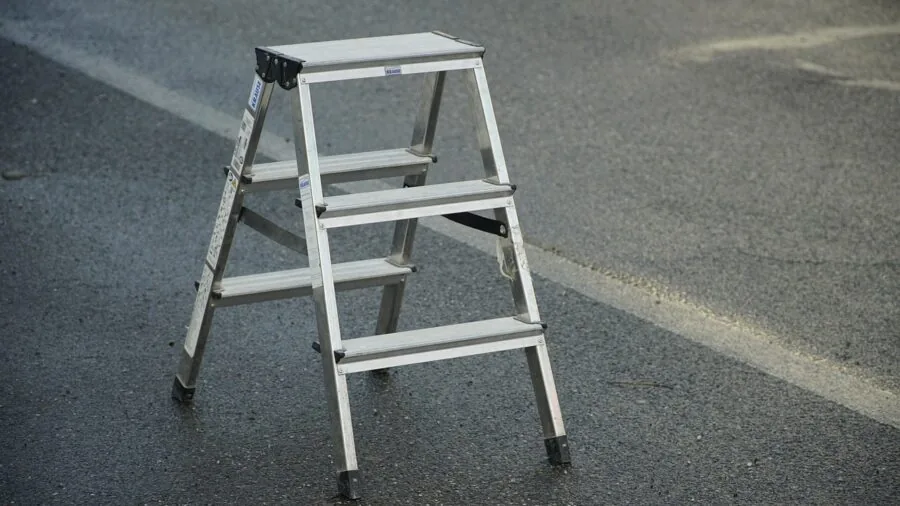 Someone installing metal step on recreational vehicle exterior during maintenance