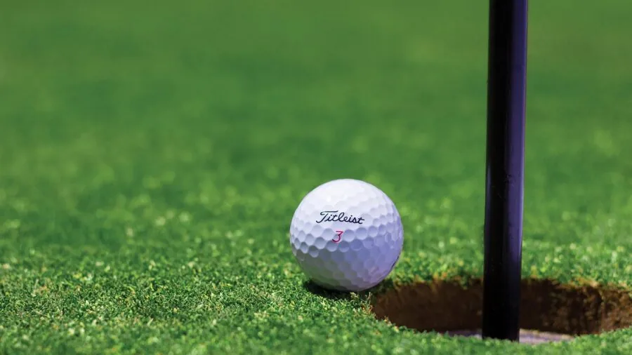 Someone practicing golf swing indoors in a home setup with natural lighting