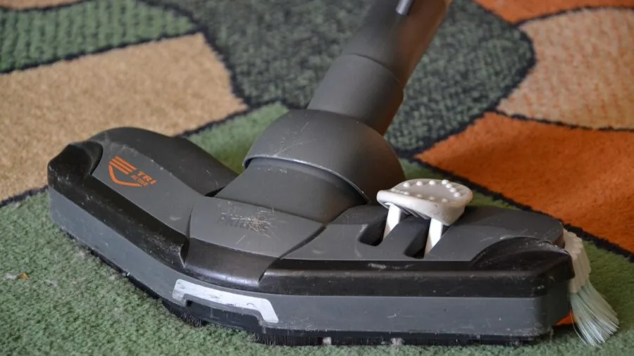 Someone using a lightweight vacuum wand to clean hardwood flooring in a home setting