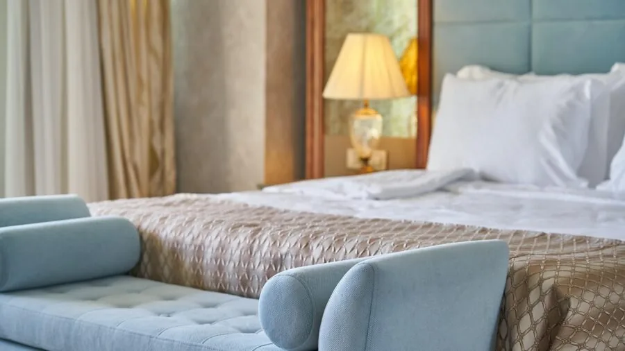 Spacious bedroom with oversized wall mirror reflecting natural light and room proportions
