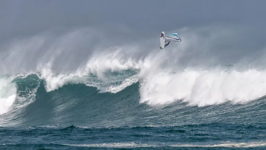 Surfer in water recovering after wipeout with bodyboard nearby, demonstrating importance of leash safety