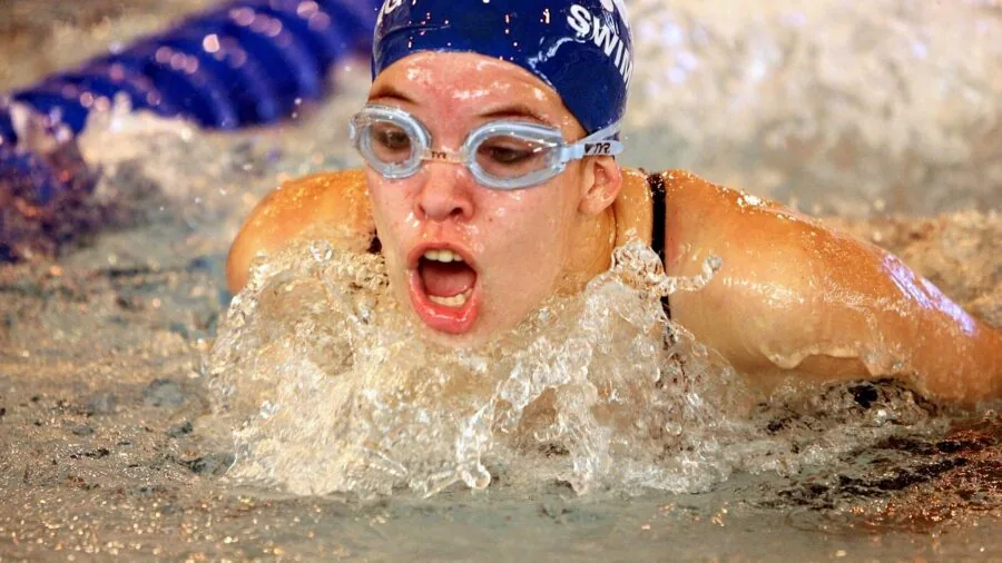 Swimmer adjusting cap before pool workout session in natural daylight