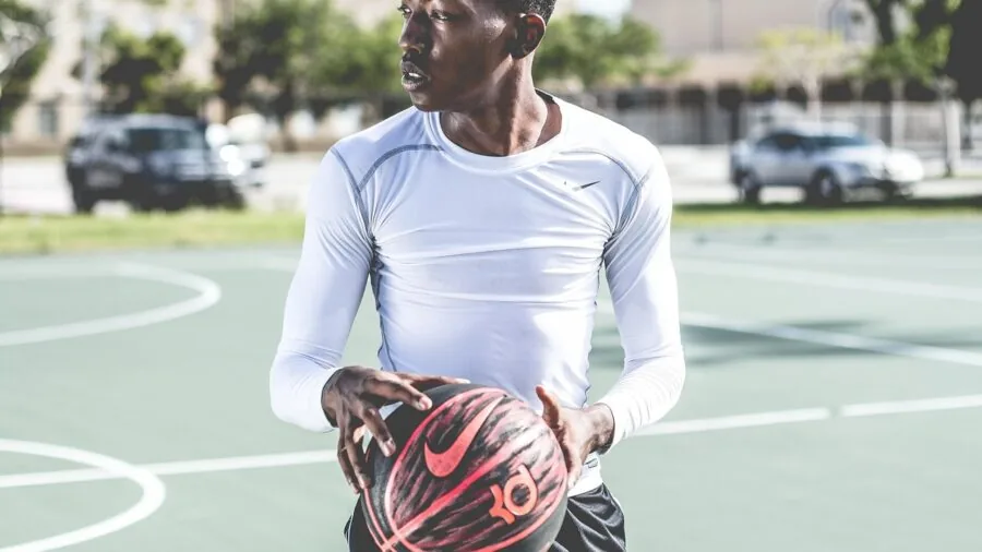 Teenager shooting basketball at outdoor court during daytime practice session