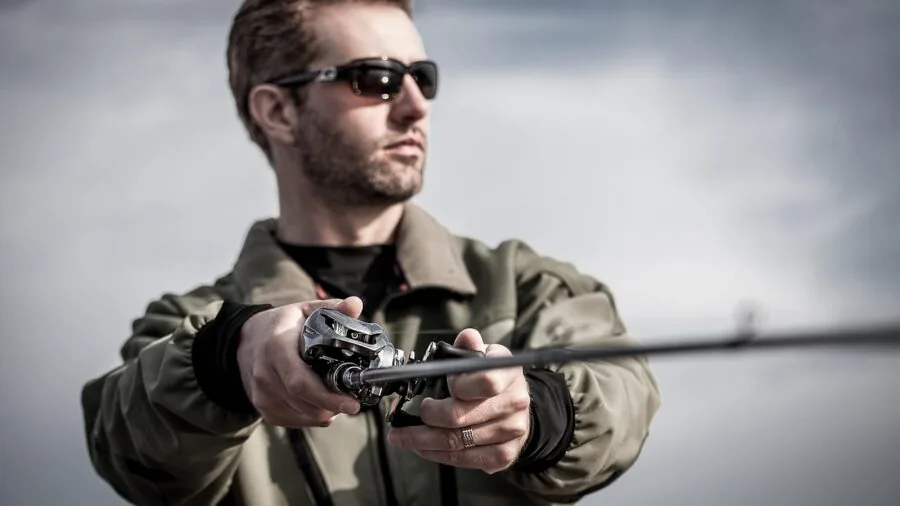Tired angler holding fishing rod during long day on water, showing physical strain of repetitive casting