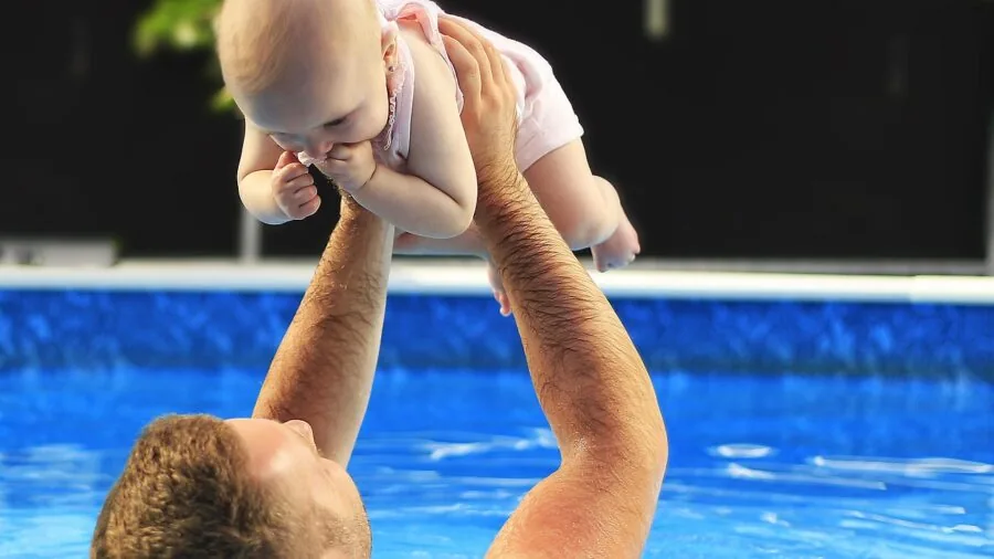 Toddler enjoying time in swimming pool with parent, demonstrating water safety and aquatic play activities