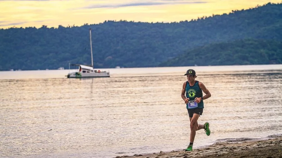 Trail runner adjusting hydration vest fit during outdoor run on sunny day