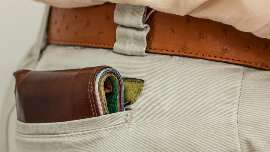 Traveler patting front pocket of jacket while navigating crowded street