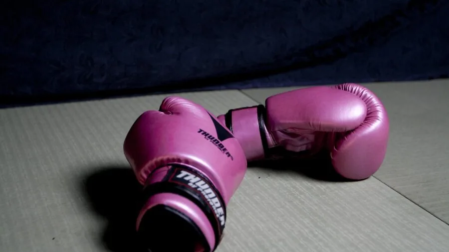 Two boxers practicing sparring techniques together in a well-lit gym with protective gear
