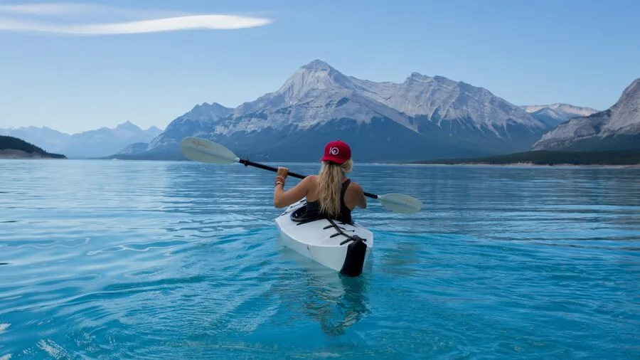 Two people paddling a tandem kayak together on still, calm water demonstrating balance and stability
