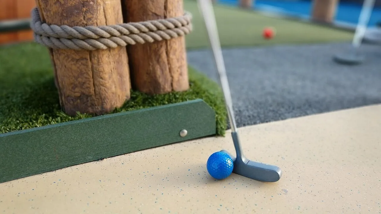 Various golf putters lined up on putting green with close-up view of putter heads