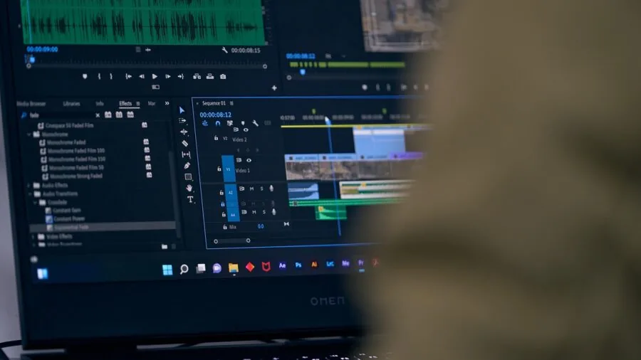 Video editor working on color grading and visual effects in a modern workspace with multiple monitors