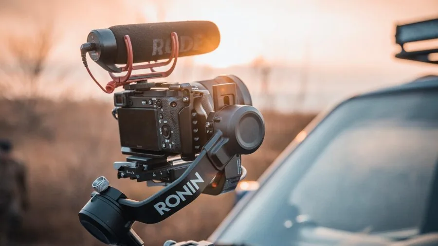 Videographer recording scenic landscape with camera equipment, demonstrating video capture quality and technique