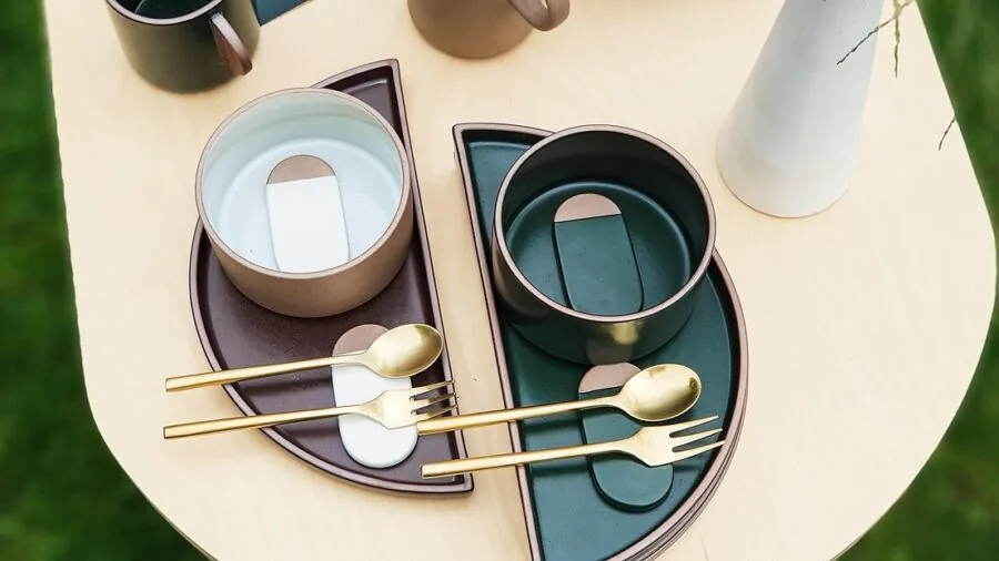 Warm minimalist table setting with organic ceramic dishes and reactive glaze bowls on wooden table