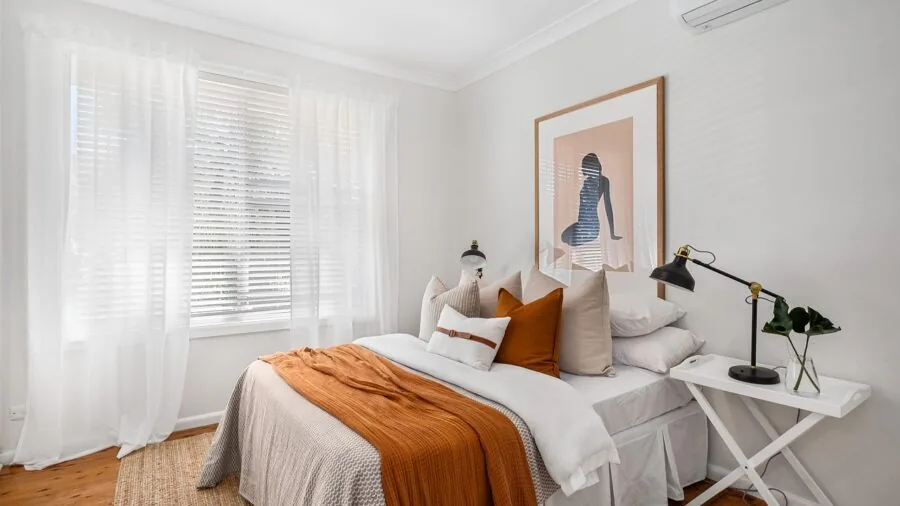 Warm table lamp on nightstand in modern bedroom interior, demonstrating proper lighting placement and style coordination