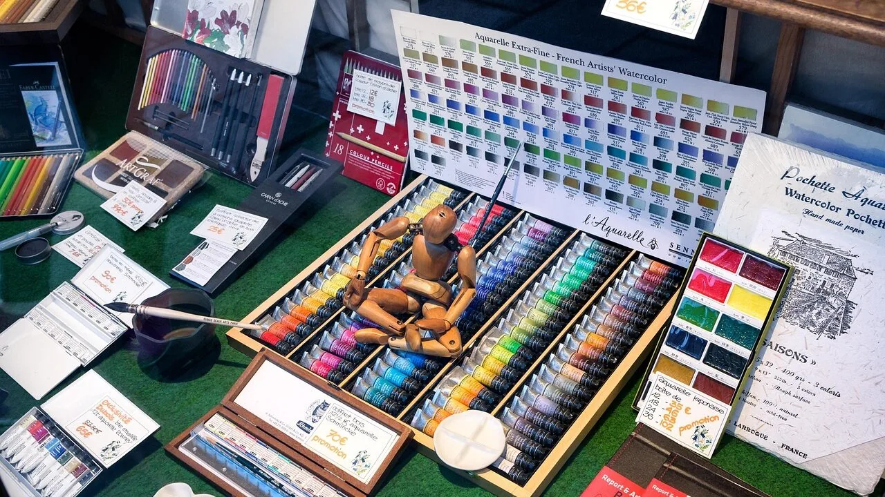 Watercolor paint sets with multiple color palettes and brushes arranged on white surface