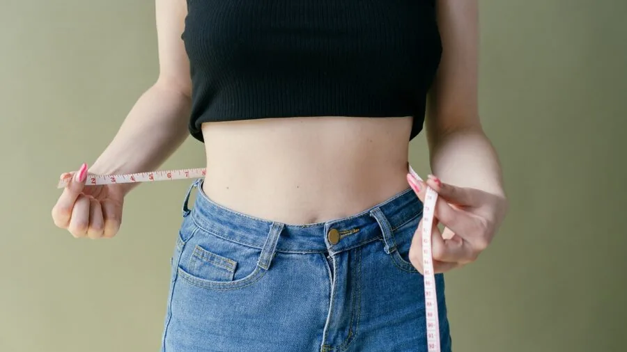 Woman adjusting her belt around her waist while looking at sizing measurements