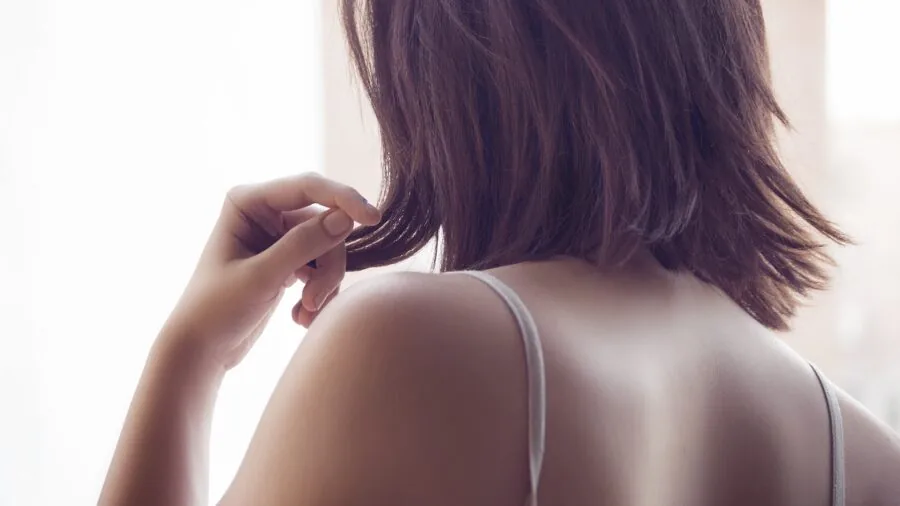Woman adjusting shoulder straps on her back, demonstrating proper fit and posture awareness in daily life
