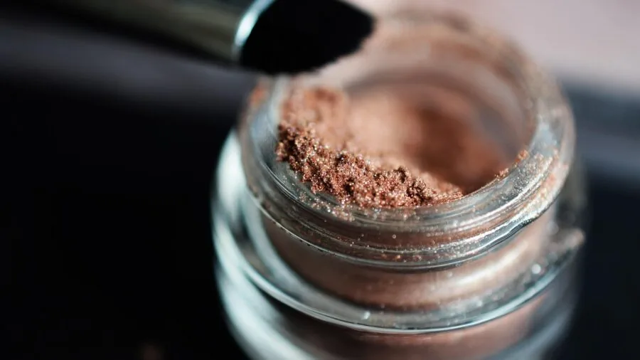 Woman applying blush makeup, focusing on natural beauty and skincare routine in natural lighting