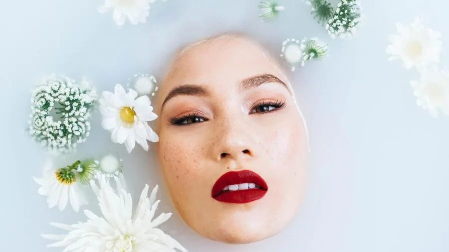 Woman applying clay face mask to her face during a relaxing skincare routine at home