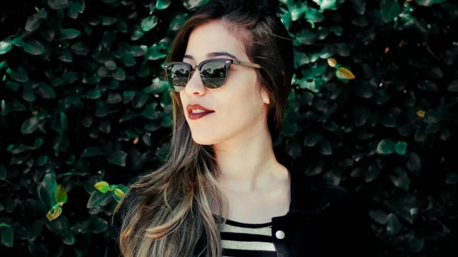 Woman applying contour makeup to cheekbones in natural lighting, demonstrating makeup application technique