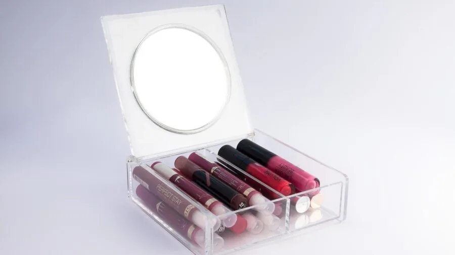 Woman applying lip gloss while looking in mirror, demonstrating comfortable glossy lip makeup application