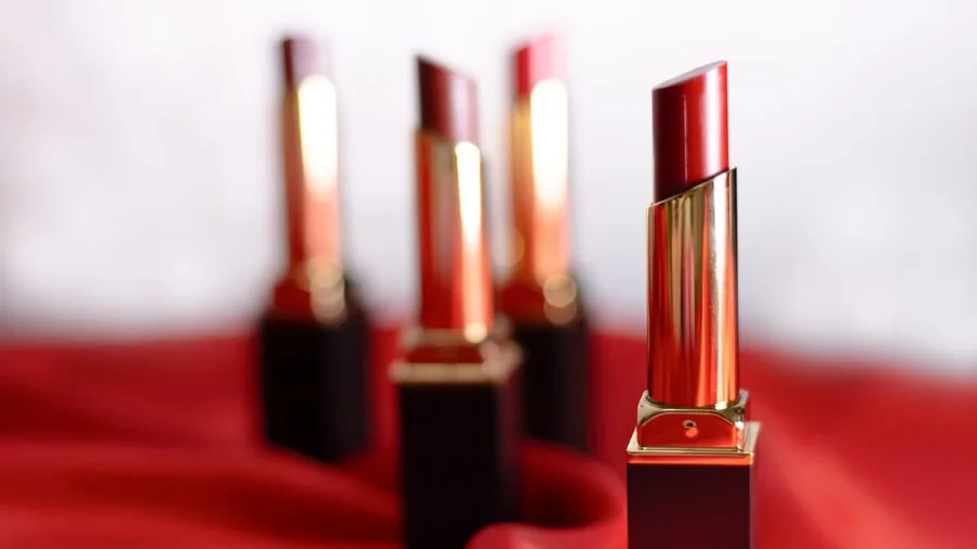 Woman applying lipstick while looking in mirror, everyday beauty routine