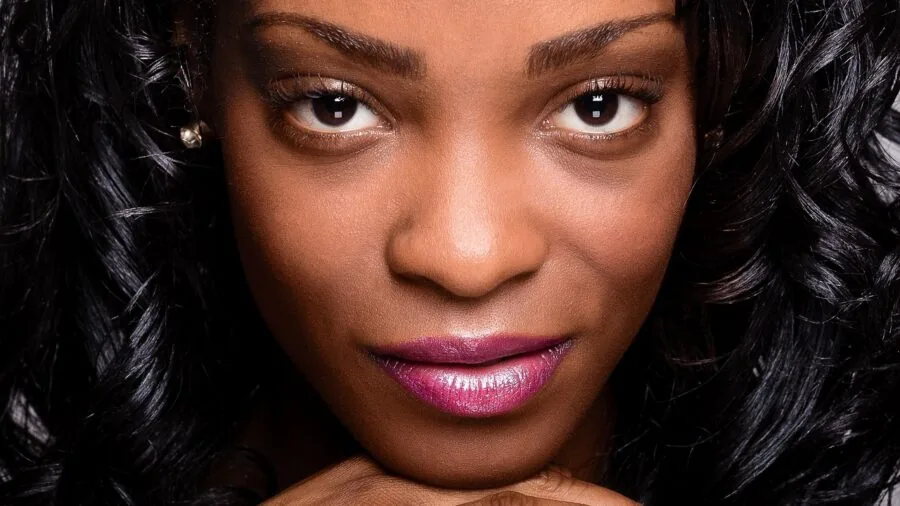 Woman applying liquid lipstick with applicator wand to lips in natural lighting