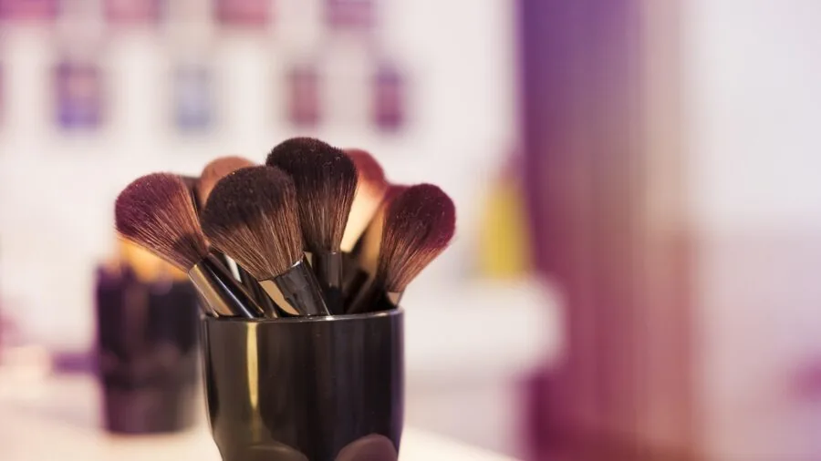Woman applying matte blush to cheeks with brush, demonstrating makeup application technique