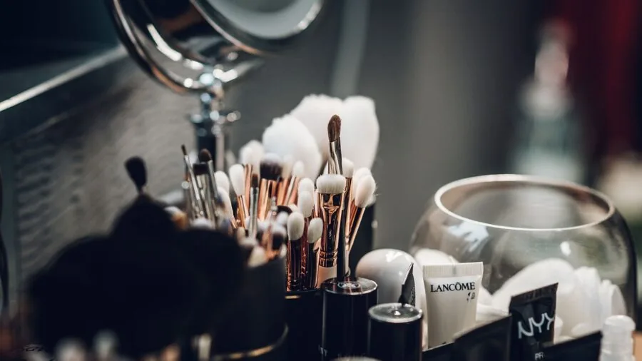Woman applying moisturizing lipstick while looking in mirror, everyday beauty routine