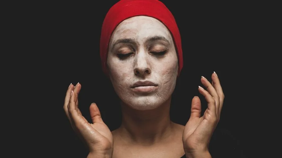 Woman applying natural clay mask to face during relaxing skincare routine at home