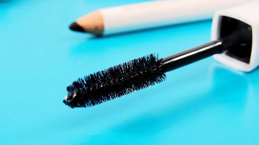 Woman applying pencil eyeliner while looking in mirror during makeup routine
