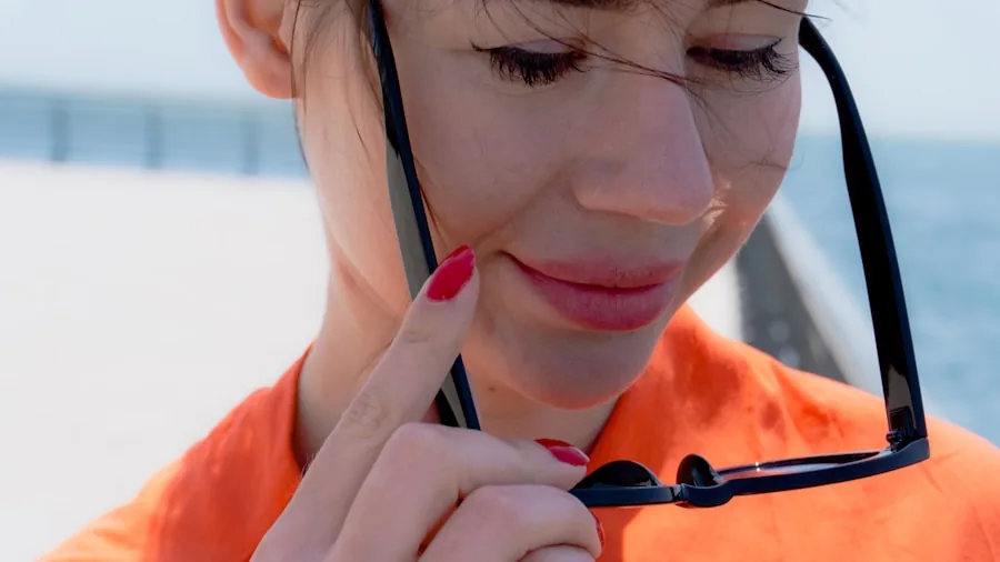 Woman applying sunscreen to face outdoors on sunny day