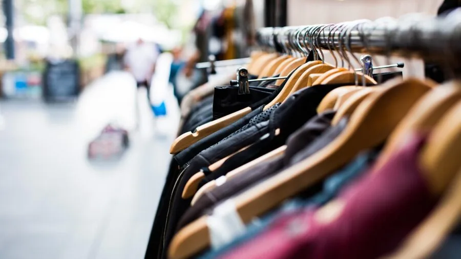Woman browsing casual dresses in retail boutique, considering affordable fashion options