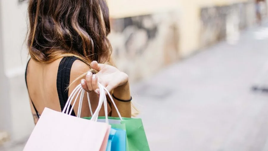 Woman browsing leather accessories at boutique store, examining wallet options