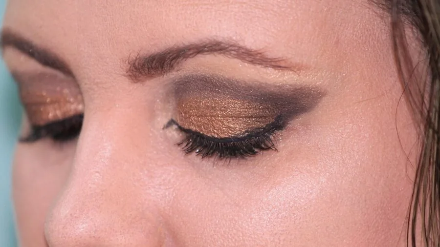 Woman carefully applying black eyeliner in natural light, demonstrating makeup application technique