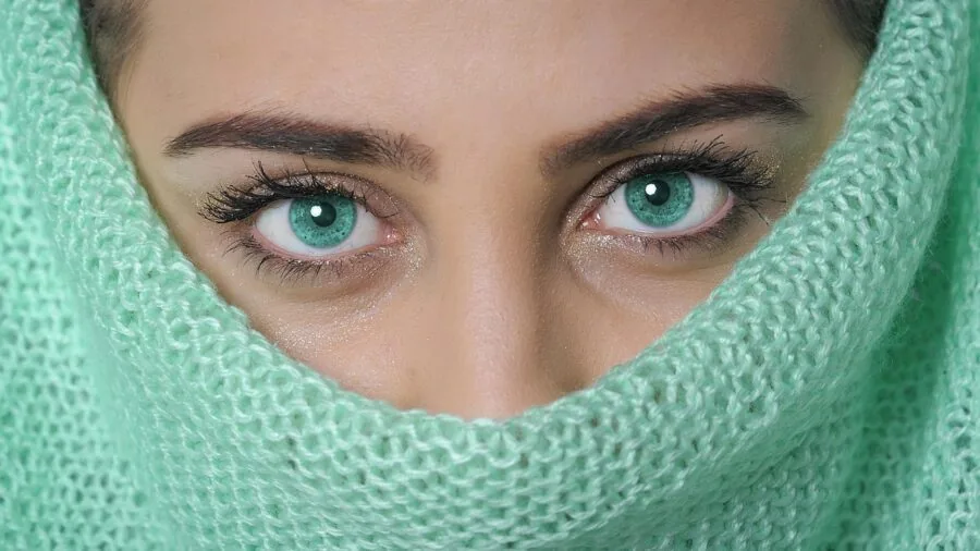 Woman carefully applying eyebrow pencil with precision technique, focusing on makeup application detail