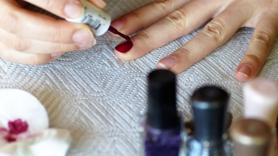 Woman carefully applying gel nail polish at home, demonstrating safe beauty practice and self-care routine