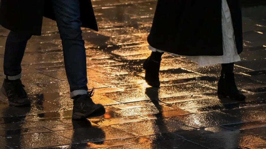 Woman confidently walking on wet city pavement in rainy weather conditions