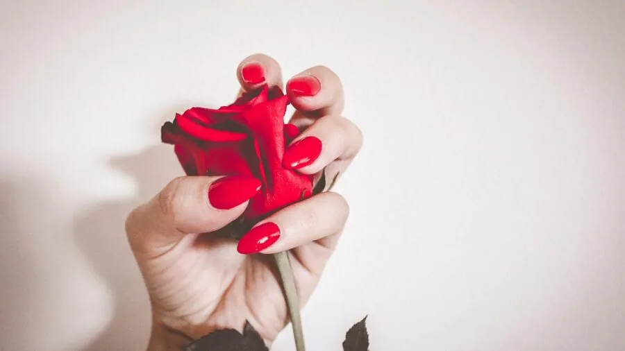 Woman doing manicure at home with natural lighting, applying gel nail polish in casual indoor setting