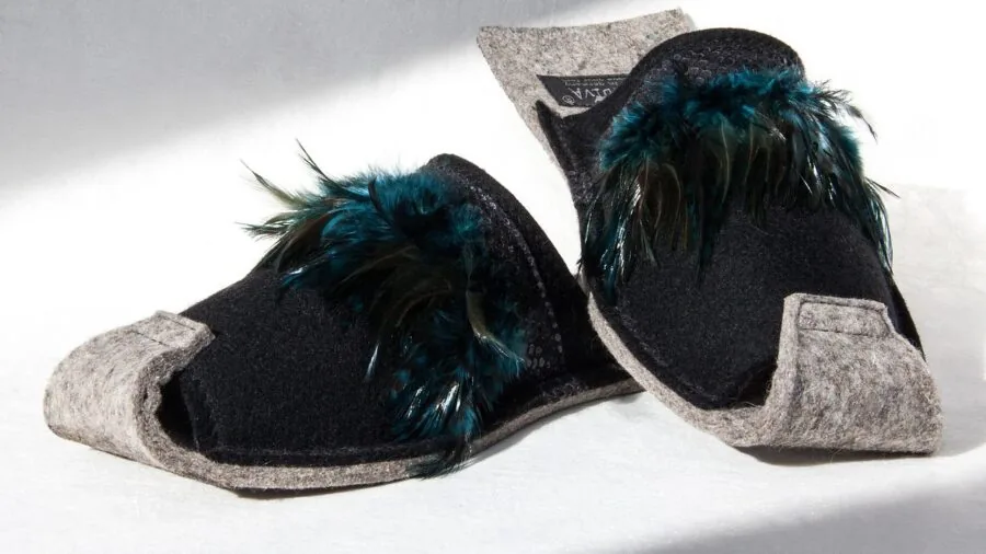 Woman easily slipping on cozy house slippers while standing in bedroom
